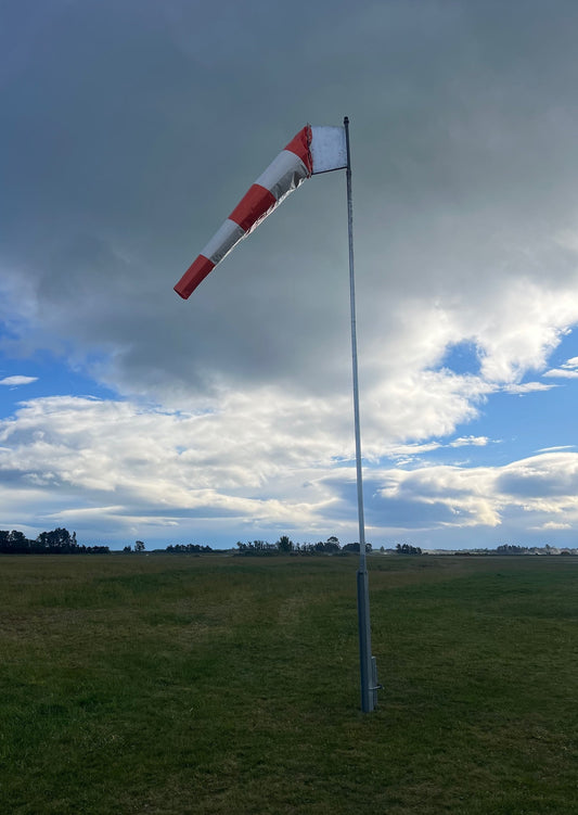 striped-windsock-on-grass-with-clouds-and-blue-skybackground
