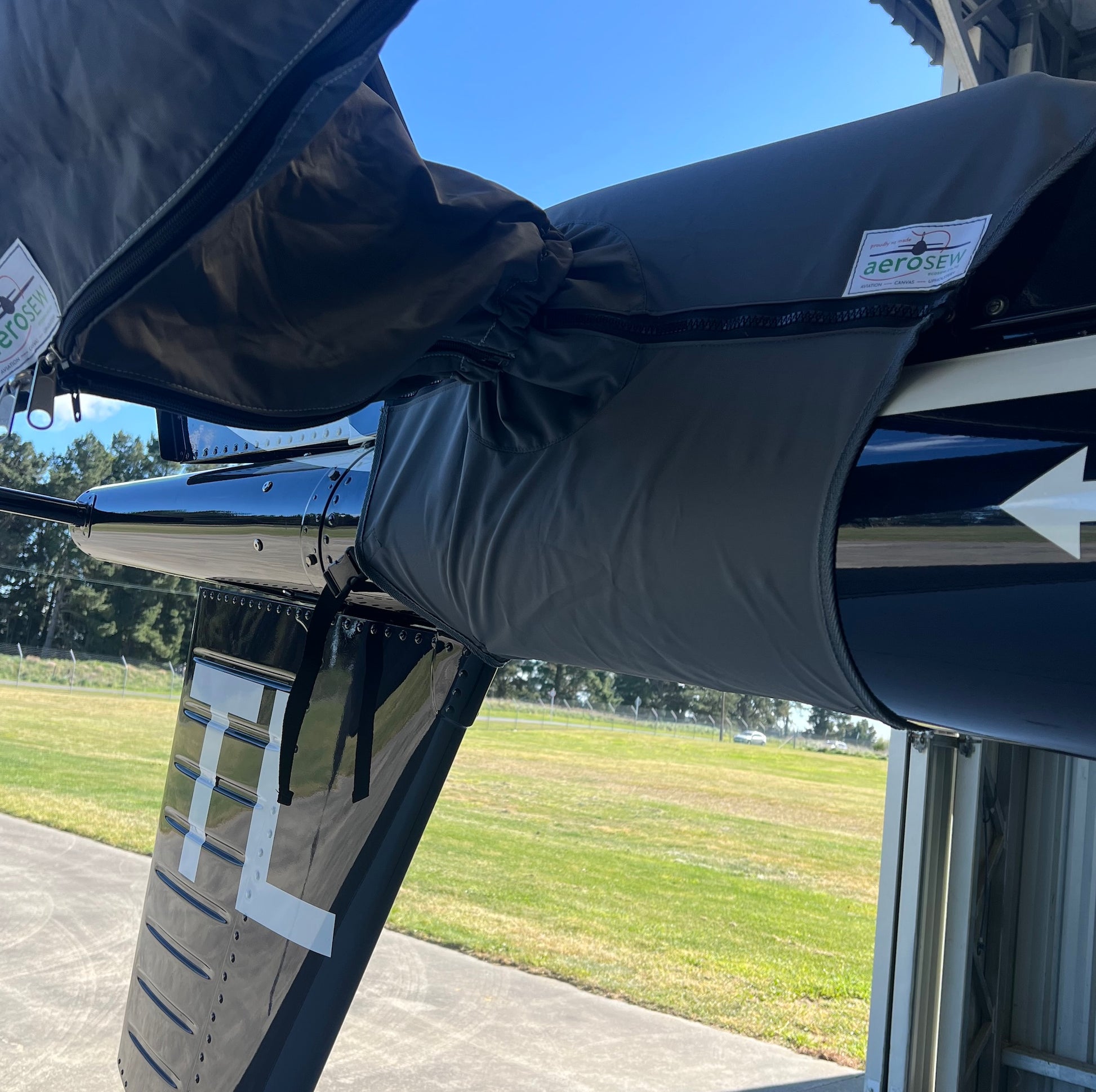 Charcoal Aerosew cover enclosing the tail rotor hub of a black H125 helicopter inside a hangar.