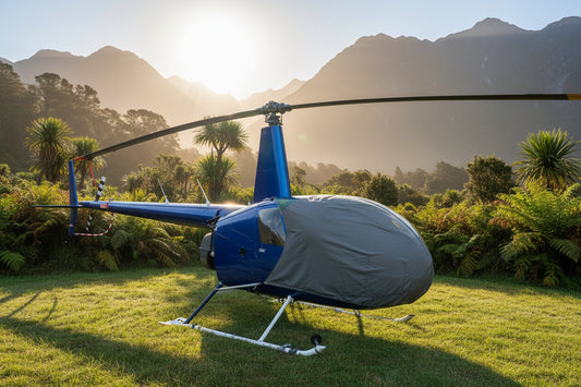 Blue helicopter with a grey aerosew  bubble cover on a grassy field under a rising sun