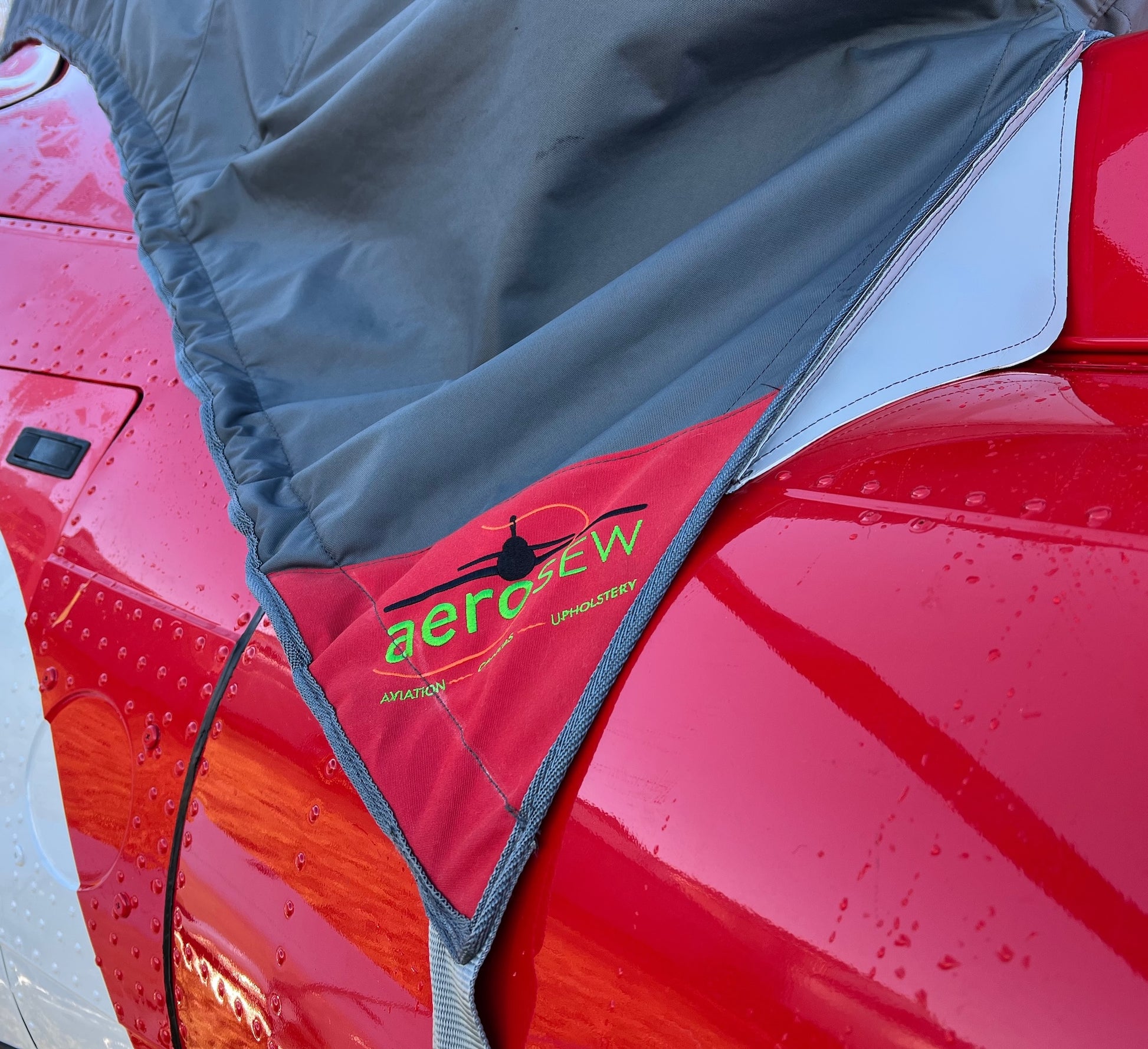 Close-up of Aerosew branded cover corner with bound edge, securing strap and protective exhaust-area lining