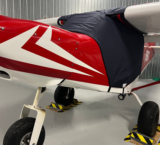red aircraft in hangar with blue aerosew cover on. 