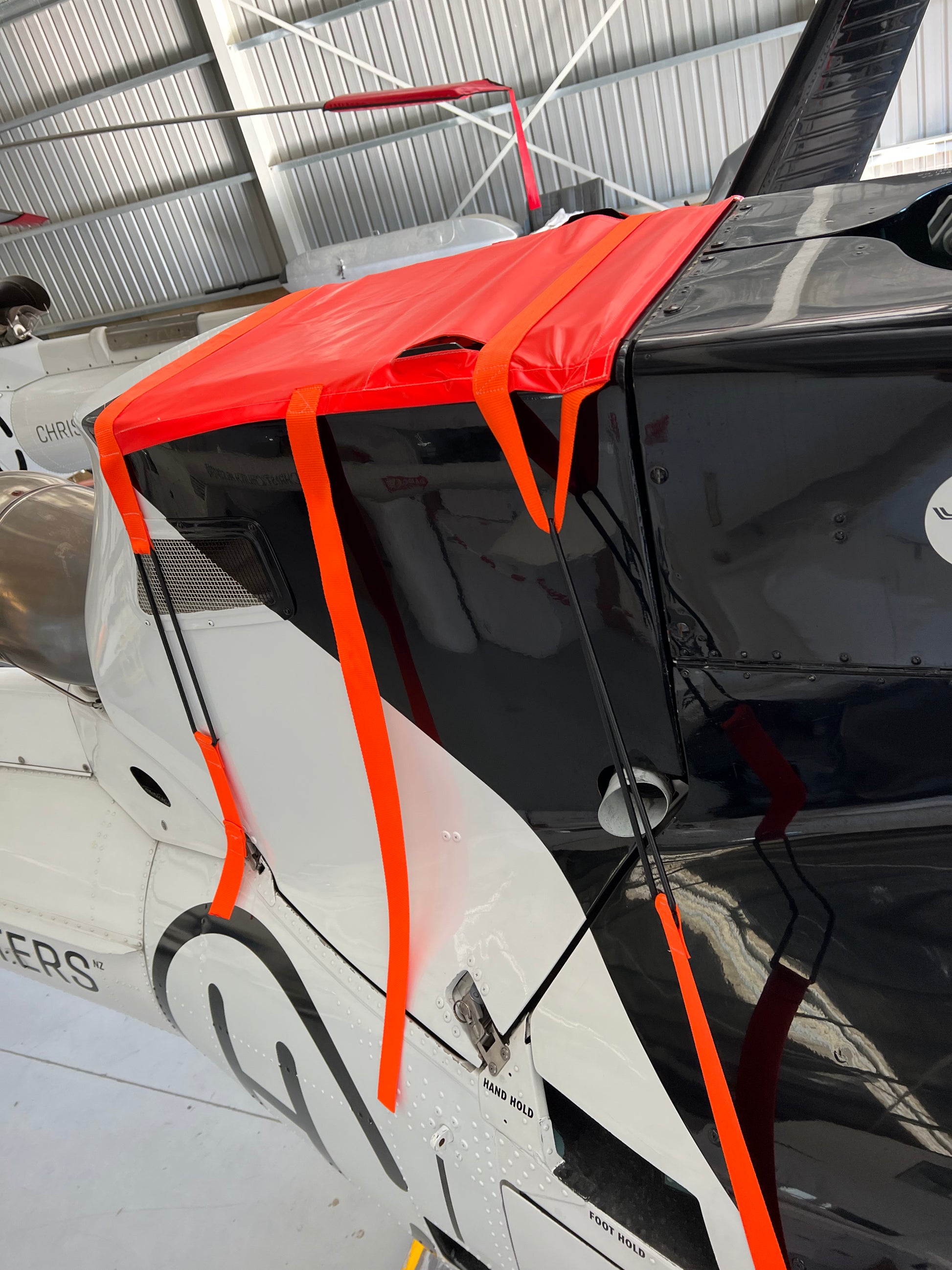 orange-aerosew-cover-on-black-squirrel-helicopter-inside-hangar