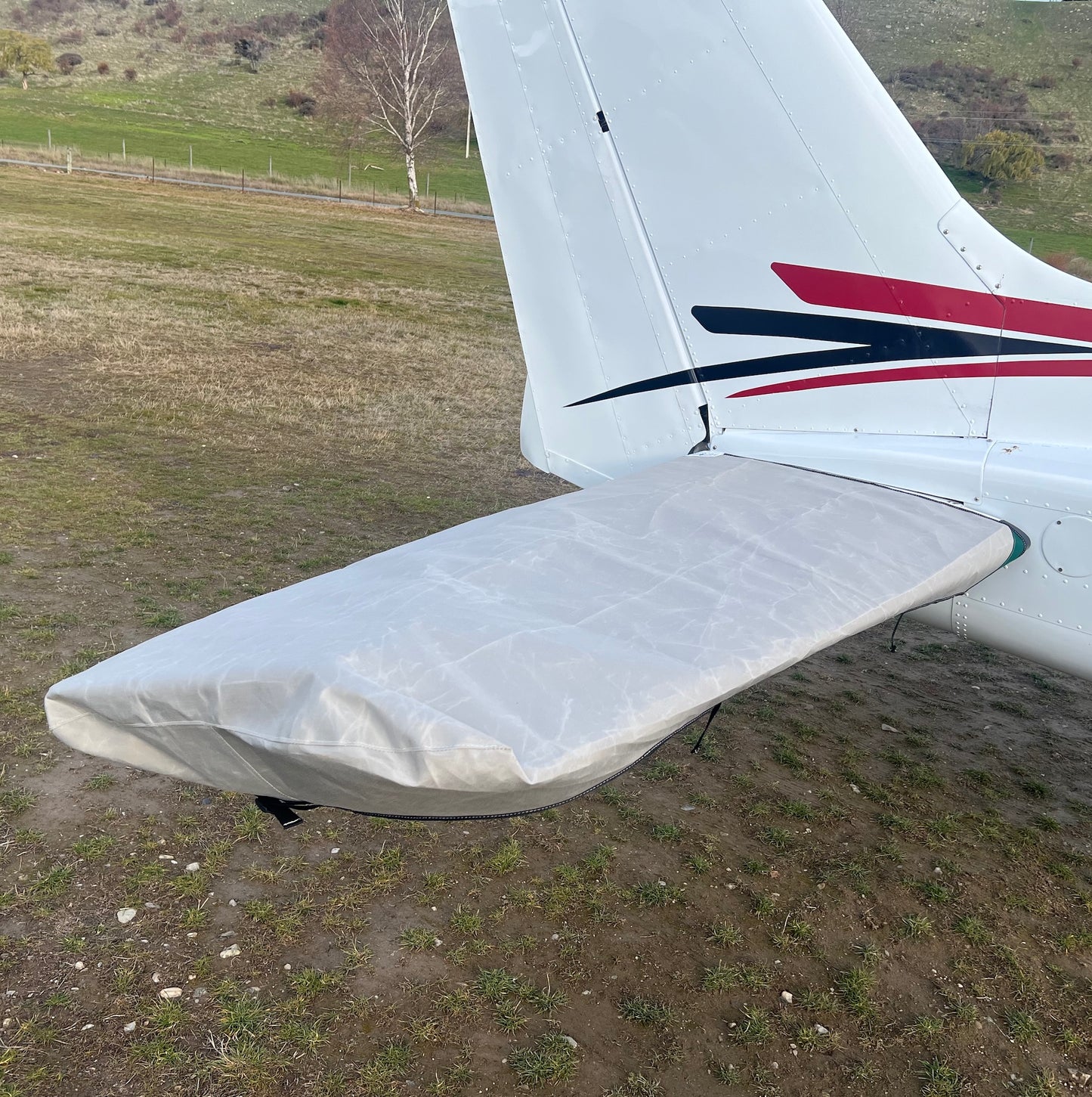 Light-grey aerosew horizontal tailplane and elevator cover fitted to one side of a white Cessna 172 aircraft