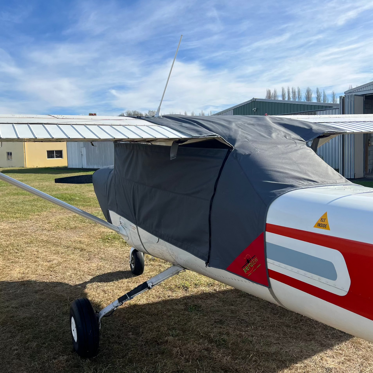 Side view of a fitted charcoal Aerosew Cessna C152 canopy cover showing the wing-root coverage and red corner marker.