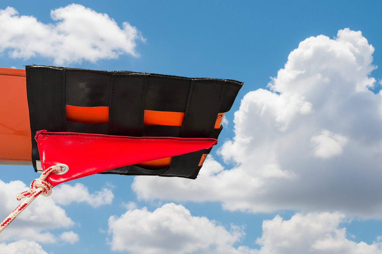 Aerosew webbing tie-down fitted around a Hughes 500 rotor blade tip against a blue sky.