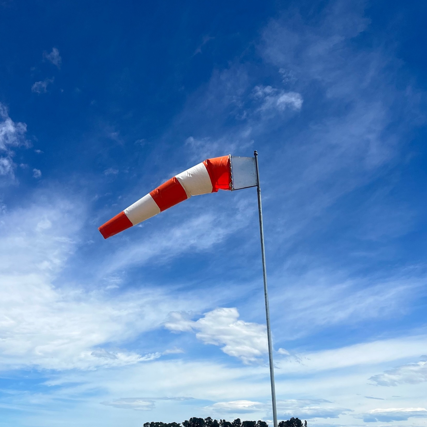 striped-windsock-against-blue-sky-with-clouds